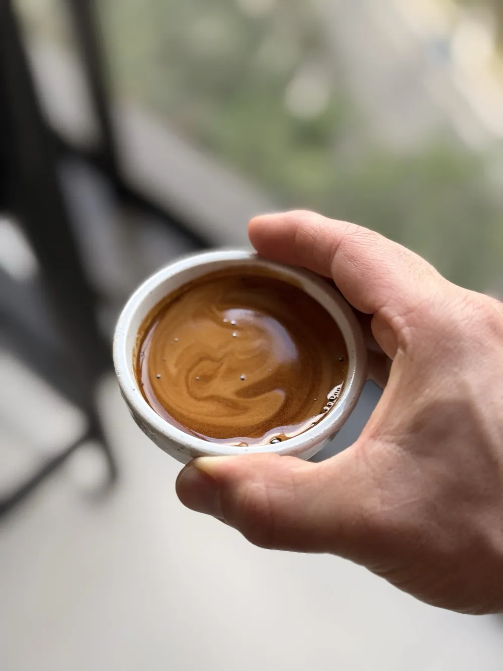 Mão segurando uma xícara de espresso Wabi com crema cor de avelã